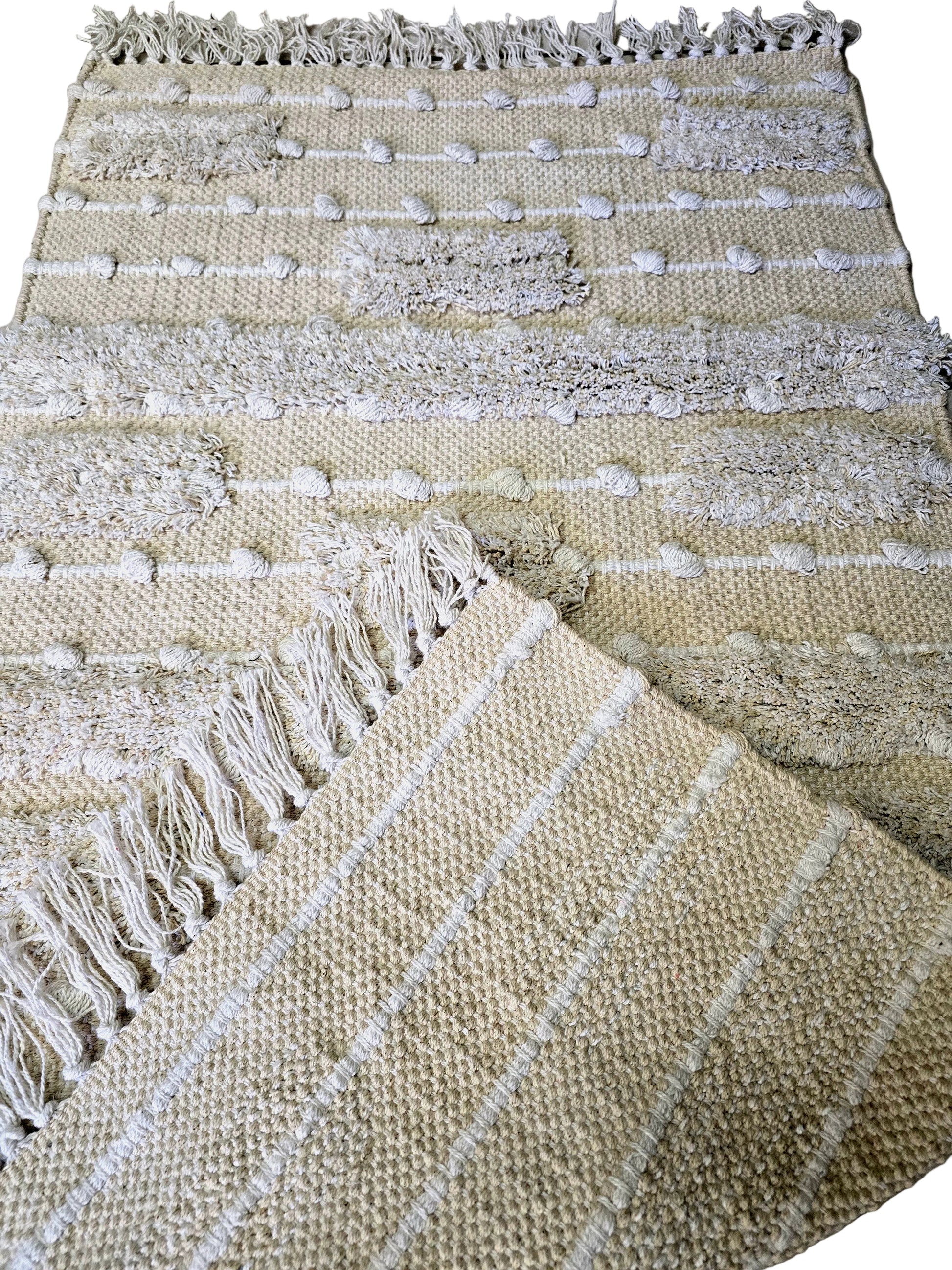 Détail du tissage en coton naturel et des motifs en relief d'un petit tapis de décoration style bohème.