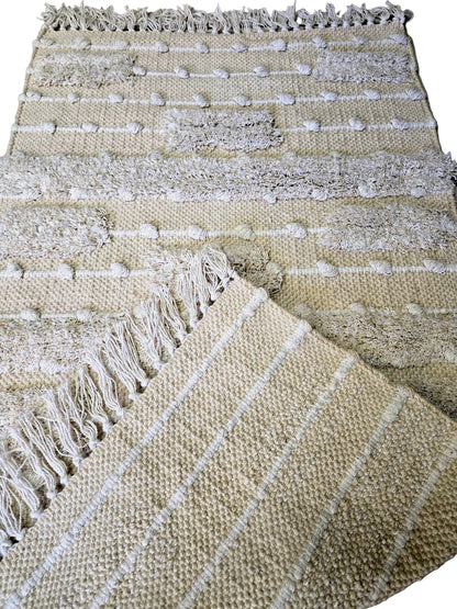 Détail du tissage en coton naturel et des motifs en relief d'un petit tapis de décoration style bohème.