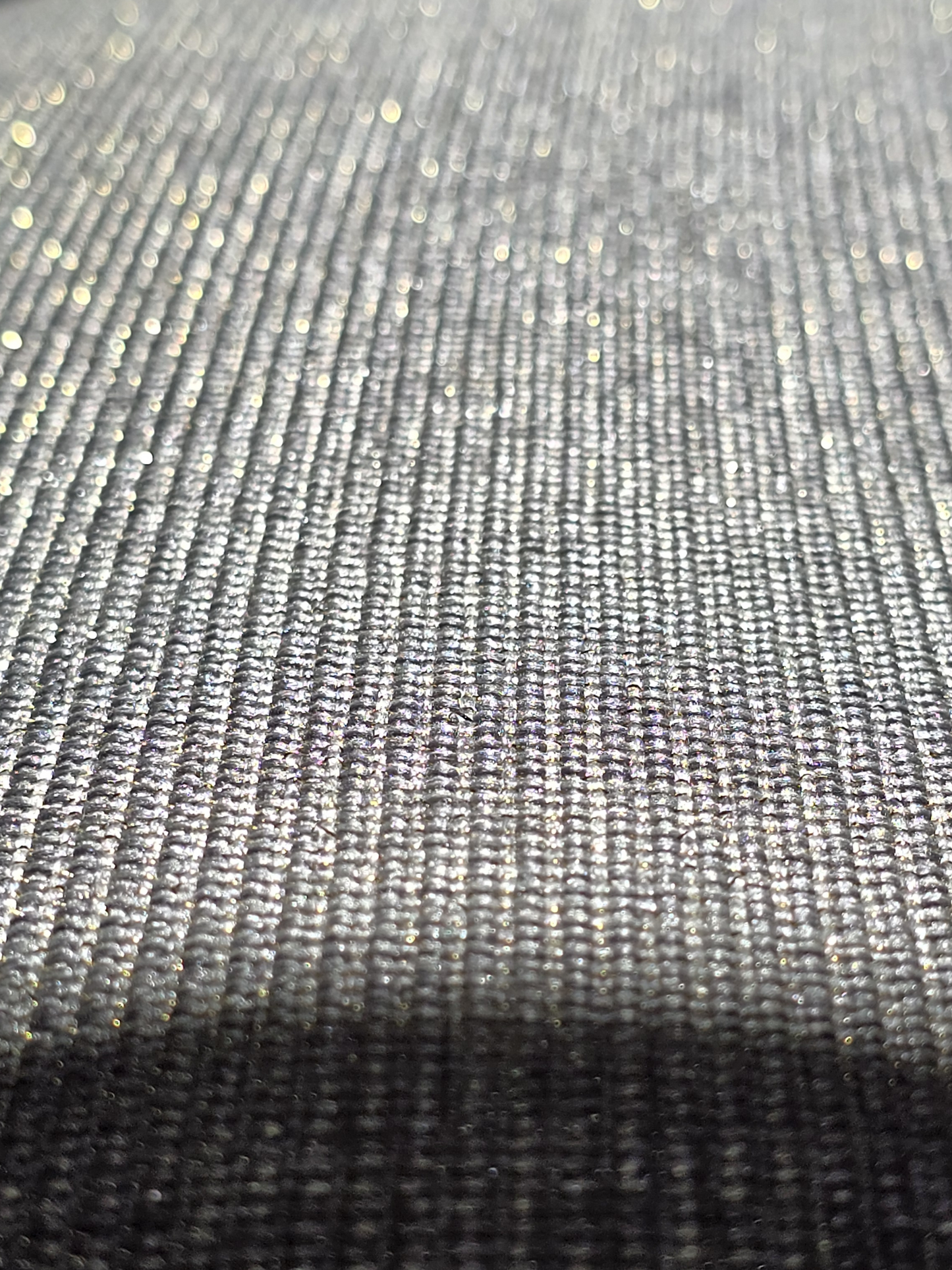 Détail de la texture du tissu gris chiné brillant réhaussé de fils dorés lurex pour un effet glamour.