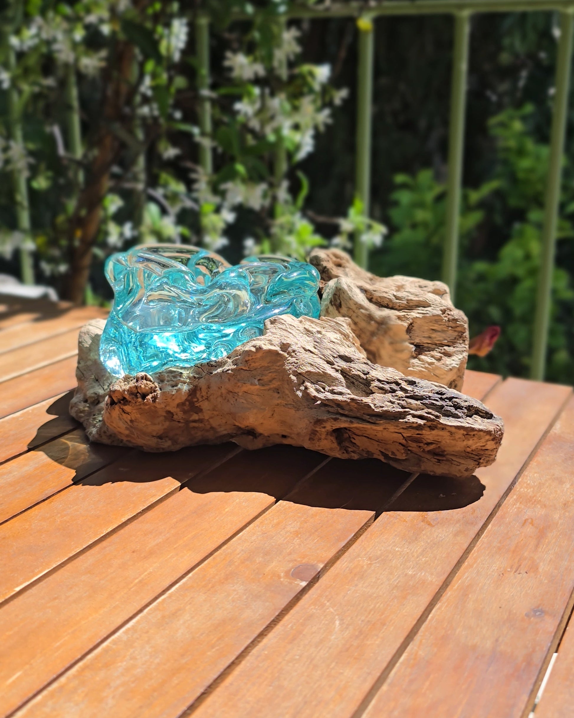Grand cendrier bois et verre soufflé turquoise 20×19×16cm vu de face, large coupe en verre aqua aux reflets cristallins posée sur souche de teck aux nervures profondes et textures brutes, fond de lames de bois — verre recyclé soufflé directement sur racine de teck, artisanat fait main Indonésie — LaPailleBambou Six-Fours-les-Plages