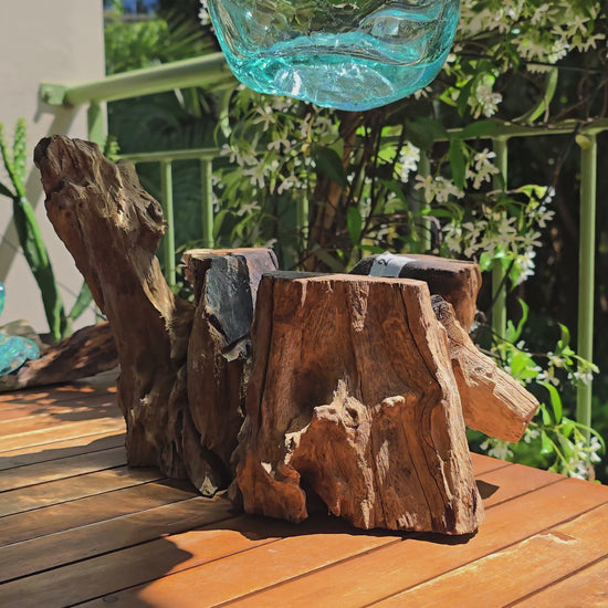Vidéo — Gros plan du grand vase à lèvres LaPailleBambou en verre soufflé recyclé sur socle en teck, présenté sur une table en bois au soleil, reflets aqua translucides — LLX ConceptStore
