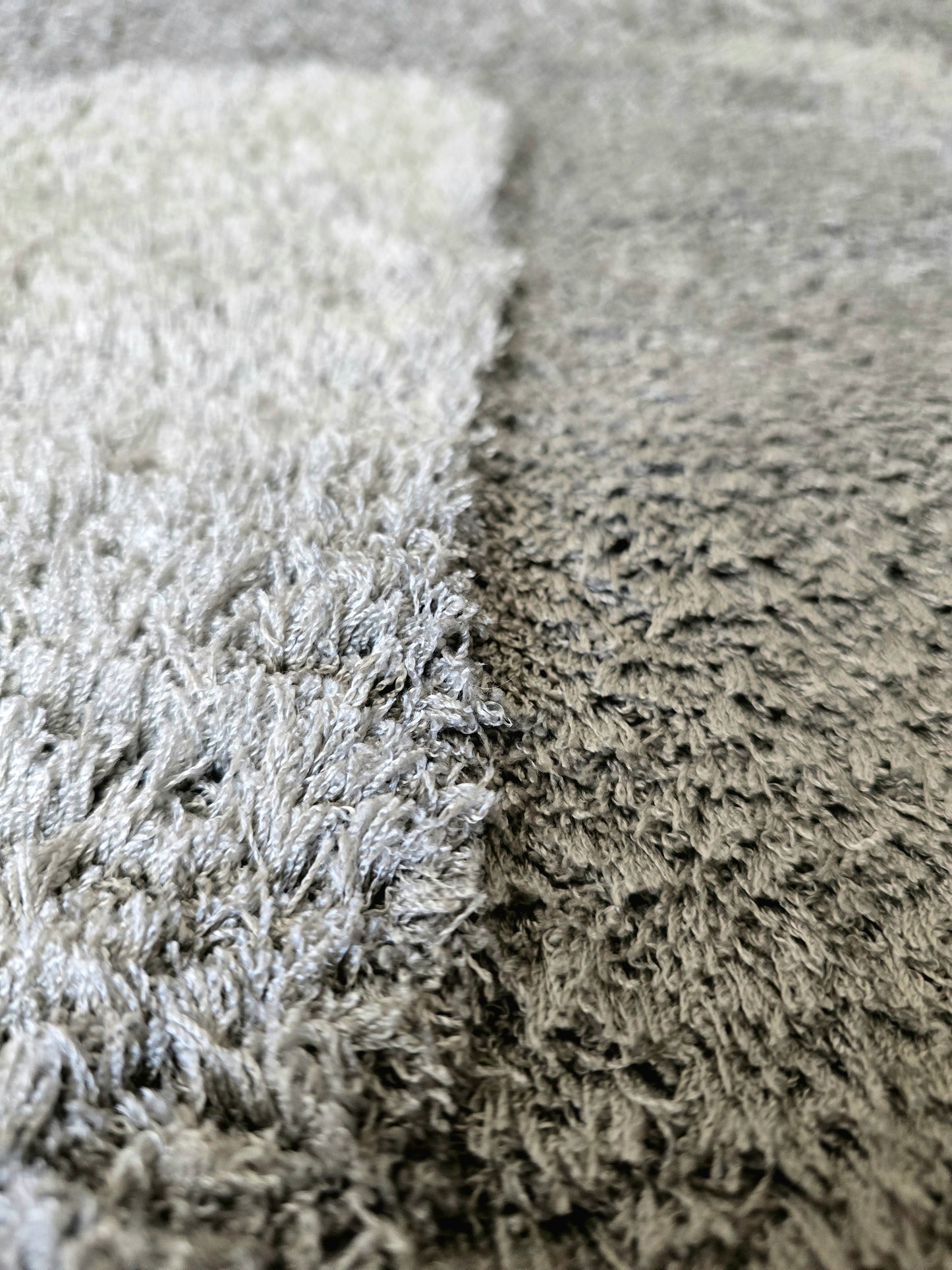 Détail de la texture sensorielle des poils longs et denses d'un tapis cocooning gris haute qualité.